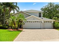 Charming two-story home with three-car garage, manicured landscaping, and a brick paver driveway at 901 Grovesmere Loop, Ocoee, FL 34761