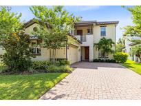 Elegant two-story home featuring a brick driveway, manicured landscaping, and a welcoming entrance at 9978 Mere Pkwy, Orlando, FL 32832