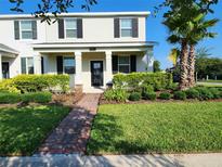 Charming townhome with a well-manicured lawn, complemented by a lovely palm tree and lush landscaping at 11802 Pulitzer Pl, Orlando, FL 32832
