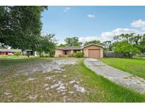 Single-story home featuring a quaint, light brown exterior with an attached garage and a spacious front yard at 2020 Cocos Ct, Winter Park, FL 32792
