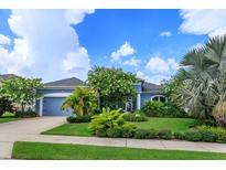 Charming blue home with a well-maintained lawn and lush landscaping at 2440 Pawtucket Pass, Mount Dora, FL 32757