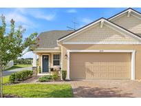 Charming single-Gathering home featuring a brick driveway, two-car garage, and covered porch at 3279 Canna Lily Pl, Clermont, FL 34711