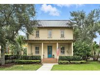 Charming two-story home with a metal roof, covered porch, manicured landscaping, and a welcoming blue front door at 4509 Belkin Ct, Orlando, FL 32814