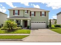 Charming two-story home with a well-manicured lawn and a spacious two-car garage at 5226 Mahogany Dr, Mount Dora, FL 32757