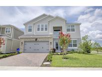 Charming two-story home features a gray exterior, well-maintained landscaping, and a brick driveway at 5310 Teirgarten St, St Cloud, FL 34771