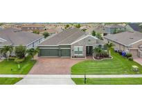 Charming single-story home featuring a three-car garage, brick paved driveway, and well-manicured lawn at 1556 Alligator St, St Cloud, FL 34771