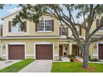 Charming townhome with a well-manicured lawn, brown shutters and a two-car garage at 1967 Beacon Bay Ct, Apopka, FL 32712