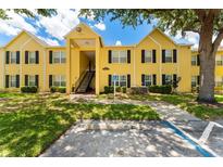 Inviting condo featuring a yellow facade, black shutters, and mature trees at 2041 Dixie Belle Dr # 2041C, Orlando, FL 32812