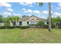 Inviting single story home featuring a well-manicured lawn, mature landscaping, and a charming blue front door at 2042 Hayfield Way, Apopka, FL 32712