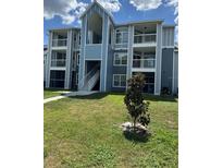 Multi-level condominium building with balconies and blue exterior paint and well-manicured lawn at 2592 Grassy Point Dr # 306, Lake Mary, FL 32746