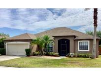 Charming single-story home featuring a well-manicured lawn, two-car garage, and tropical landscaping at 2831 Village Pine Ter, Orlando, FL 32833