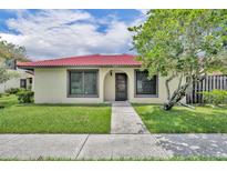 Charming single-story home with a red tile roof, lush lawn, and mature shade tree at 557 Hunter Cir, Kissimmee, FL 34758