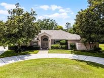 Charming single-story home featuring circular driveway, mature trees, and manicured landscaping at 707 Heritage Ne Dr, Winter Haven, FL 33881