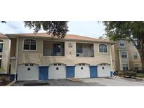 Charming condo building exterior with tan stucco, blue accents, and private balconies over garages at 7220 Westpointe Blvd # 1429, Orlando, FL 32835