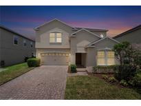 Charming two-story home with a brick driveway and well-manicured landscaping at twilight at 7409 Fairgrove Ave, Windermere, FL 34786