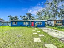 Charming blue home with a bright red door and a well-manicured lawn, set beneath a beautiful blue sky at 91 High St, Winter Haven, FL 33880
