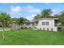 Charming one-story home with a green lawn, complemented by flowering plants and a well-maintained landscape at 941 Grey Oak Ct, Orlando, FL 32809