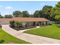 Single-story home featuring a lush front lawn, driveway, and mature landscaping at 1191 Banbury Trl, Maitland, FL 32751