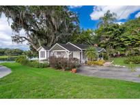 Charming white cottage-style home with mature trees, lush lawn, and a waterfront view at 1504 E Gore St, Orlando, FL 32806