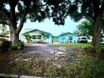 Charming, turquoise home with a well-manicured lawn and mature trees framing the facade at 1811 Missouri Ave, Sanford, FL 32771