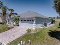 Charming single-story home with a brick driveway and attached two-car garage, surrounded by lush landscaping at 204 Birkdale St, Davenport, FL 33897