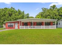 Charming single story red brick home with a large covered front porch and a green lawn at 3016 Rogan Rd, Orlando, FL 32812