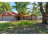 Charming single-story home featuring a brick facade, mature trees, and a well-maintained lawn at 3237 Newmark Dr, Deltona, FL 32738