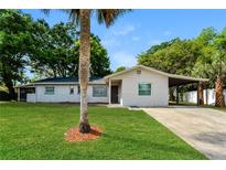 Charming single-story home with a well-manicured lawn, carport, and lovely front yard tree at 4 Kasey Dr, Orlando, FL 32807