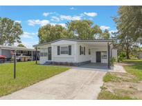 Charming single-story home with a carport and well-maintained front lawn in a quiet community at 814 Roseapple Ave, Lady Lake, FL 32159