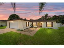 Charming single-story home with a well-manicured lawn, lovely sunset and attached garage at 909 Hendon Place, Kissimmee, FL 34758