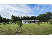 Charming single story home with a large front yard, mature trees, and beautiful landscaping at 13208 Massachusetts Ave, Astatula, FL 34705