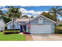 Charming single-Gathering home featuring a manicured lawn, mature palm trees, and a two-car garage with an American flag at 14529 Falling Tree Ct, Orlando, FL 32837