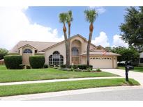 Charming beige home with manicured lawn, arched windows, and palm trees at 1546 Royal Cir, Apopka, FL 32703