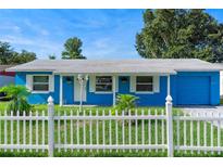 Charming blue single-story home featuring a white picket fence, green lawn, and blue sky at 4654 Alhama St, Orlando, FL 32811