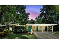 Charming home with a covered carport, vibrant turquoise door, and lush, mature landscaping creates a welcoming curb appeal at 509 Altaloma Ave, Orlando, FL 32803