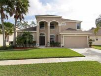 Charming two-story home with a manicured lawn, complemented by palm trees and a two car garage at 531 Canary Island Ct, Orlando, FL 32828
