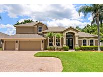 Elegant home featuring a paver driveway, three-car garage, manicured lawn, and front landscape at 748 Duff Dr, Winter Garden, FL 34787