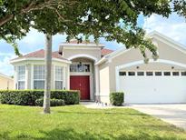 Charming single-Gathering home showcasing manicured landscaping, arched entry, and a red front door at 8023 King Palm Cir, Kissimmee, FL 34747