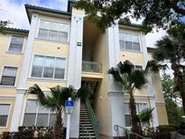 Condo building with stairs, palm trees, and a handicap parking sign in front at 8929 Legacy Ct # 208, Kissimmee, FL 34747