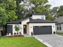 Contemporary home features a black roof, a two-car garage, and a beautifully landscaped front yard at 1526 Hempel Ave, Gotha, FL 34734