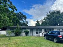 Cozy single-story home featuring a well-maintained front yard and a modern car parked beside the house at 223 Hope Cir, Orlando, FL 32811