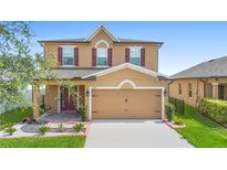 Charming two-story home with a well-manicured lawn, landscaping and a covered porch with swing at 2254 Canyon Breeze Ave, Kissimmee, FL 34746