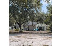 Charming single-story home featuring an attached garage, mature trees and a spacious, sandy front yard at 32645 Red Oak Dr, Eustis, FL 32736