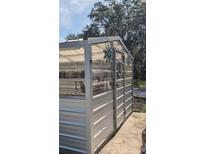 A greenhouse featuring metal construction with transparent panels, door, and decorative flower accents at 32645 Red Oak Dr, Eustis, FL 32736