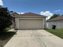 Attached two-car garage with a concrete driveway on a sunny day with white fence in view at 5118 Laval Dr, Orlando, FL 32839