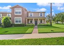 Inviting two-story home featuring a well-maintained lawn, charming entryway, and neutral-tone facade at 5669 New Independence Pkwy, Winter Garden, FL 34787
