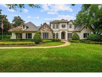 Stunning two-story home with a lush green lawn, manicured landscaping, and stone accents at 6138 Greatwater Dr, Windermere, FL 34786