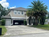 Inviting two-story home featuring a spacious driveway, attached two-car garage, and a mature palm tree in the front yard at 860 Charlotte St, Longwood, FL 32750
