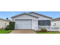 Charming single story home with manicured lawn, white picket fence, attached two car garage, and attractive landscaping at 9376 Se 175Th Pompion St, The Villages, FL 32162