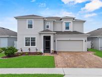 Two-story home featuring a well-kept lawn, brick driveway and a two-car garage, with a charming gray color palette at 944 Benjamin Trl, Davenport, FL 33837